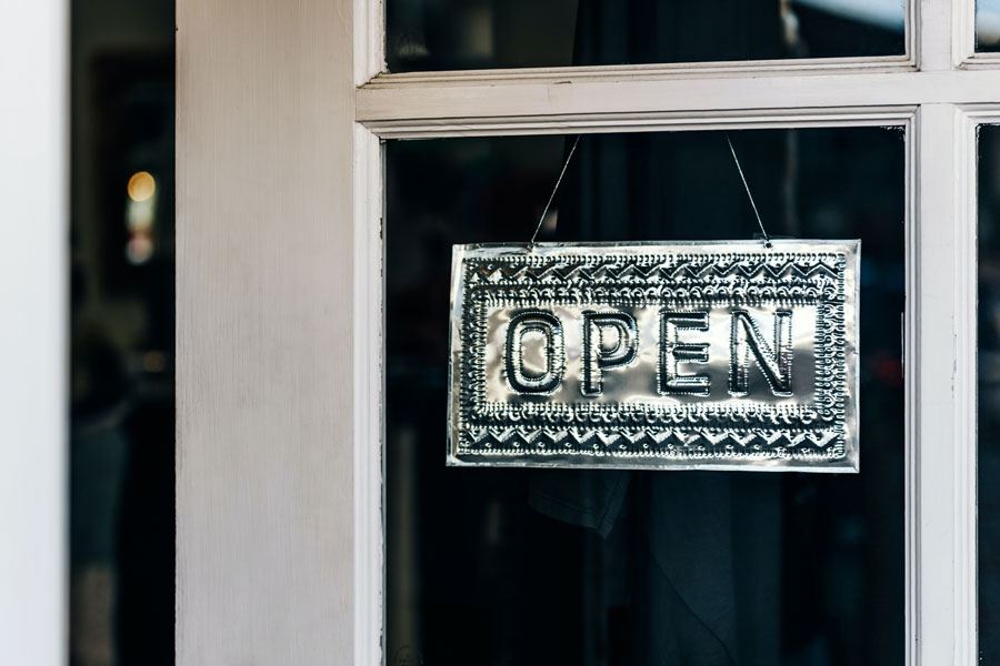 Photo: "Open" sign in pressed tin hangs in a window